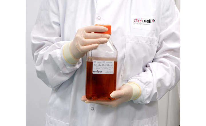 Scientist holds a 1 litre plastic bottle of Redipor prepared media